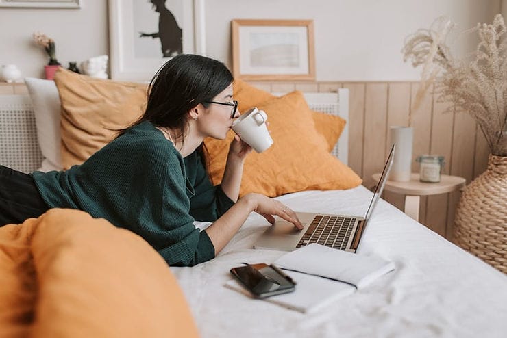 woman in bed checking laptop