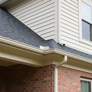 close-up of seamless gutters next to traditional sectional gutters on a brick and vinyl-siding home